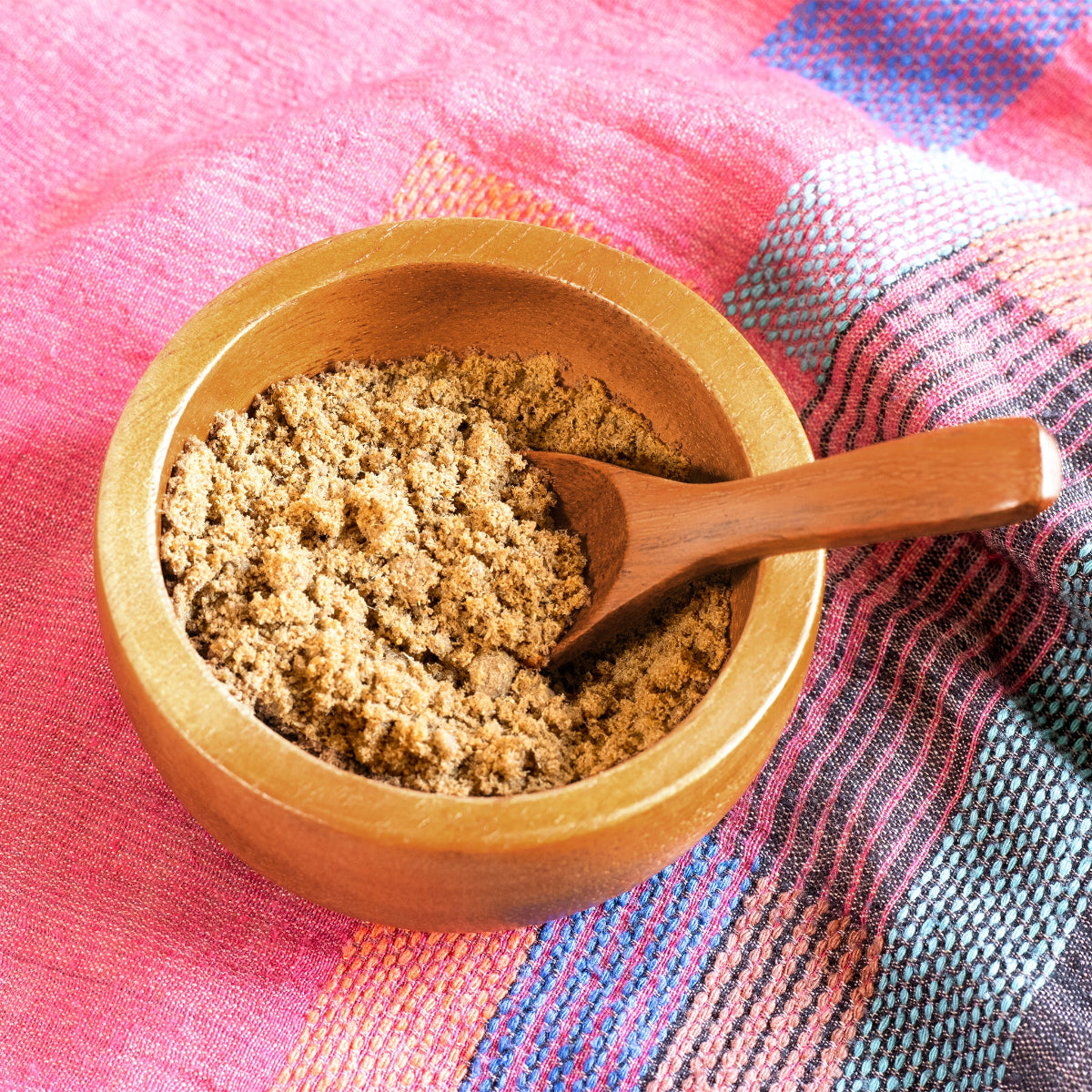 Amla & Pracaxi hair mask in a wooden bowl on a colorful fabric.