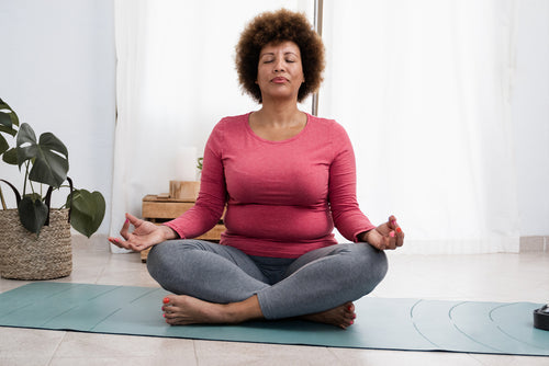 Woman doing pranayama breath exercises during yoga session at home.