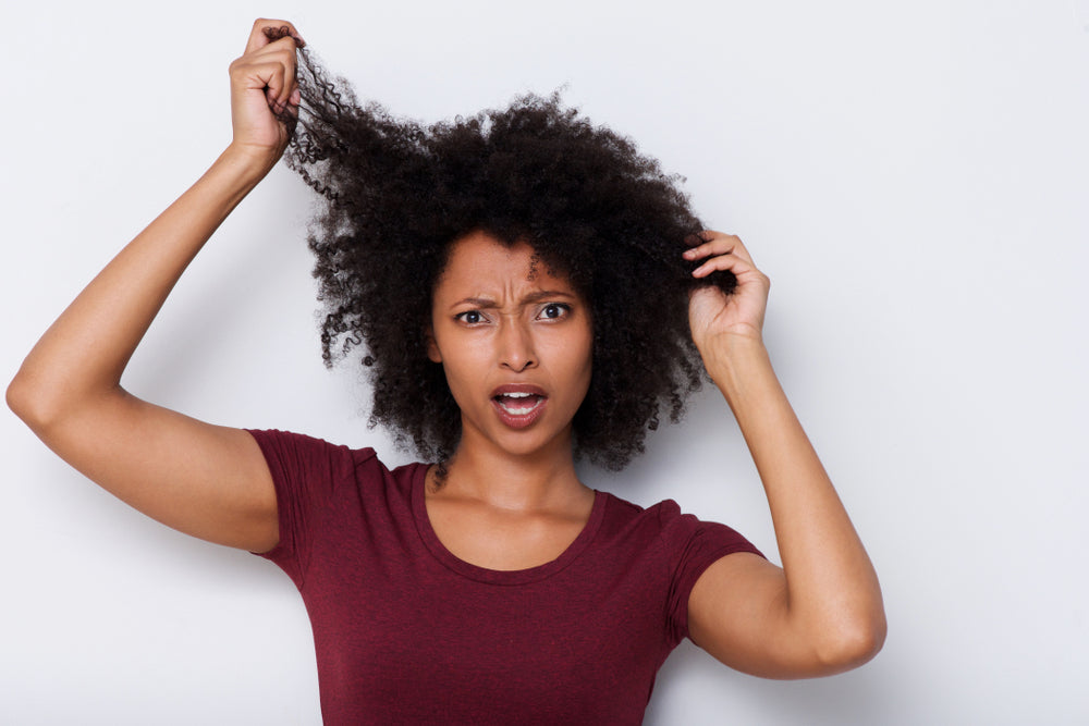Close-up of a woman pulling her hair and looking worried.