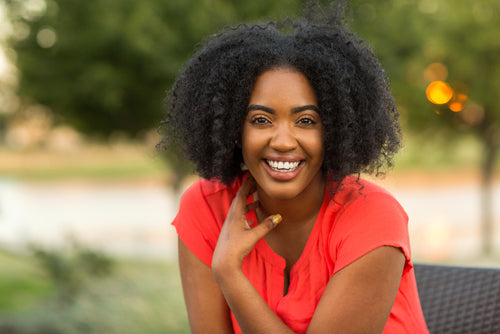 Woman with natural hair smiling warmly, showing joy and confidence.