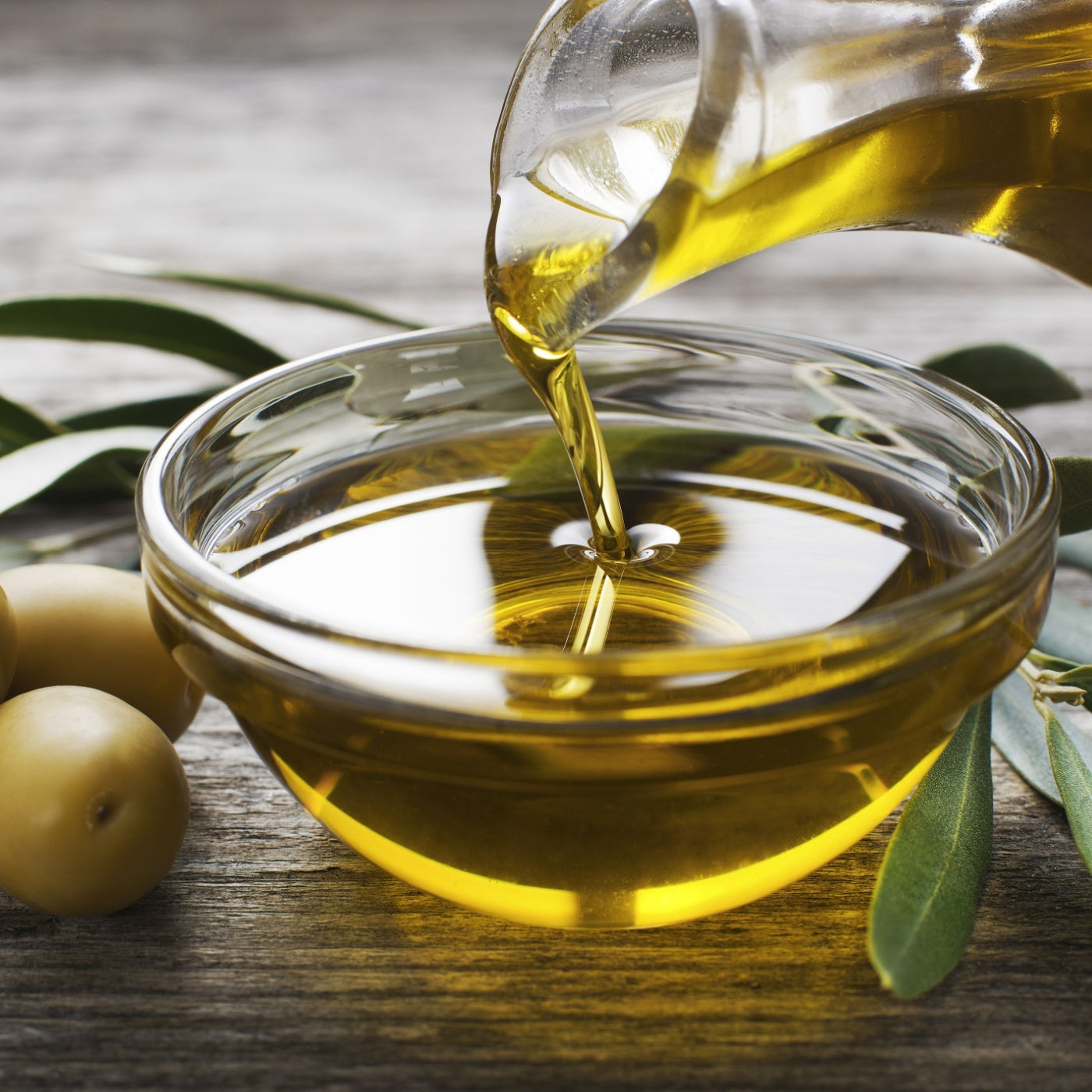 Bottle pouring virgin olive oil in a bowl close up.